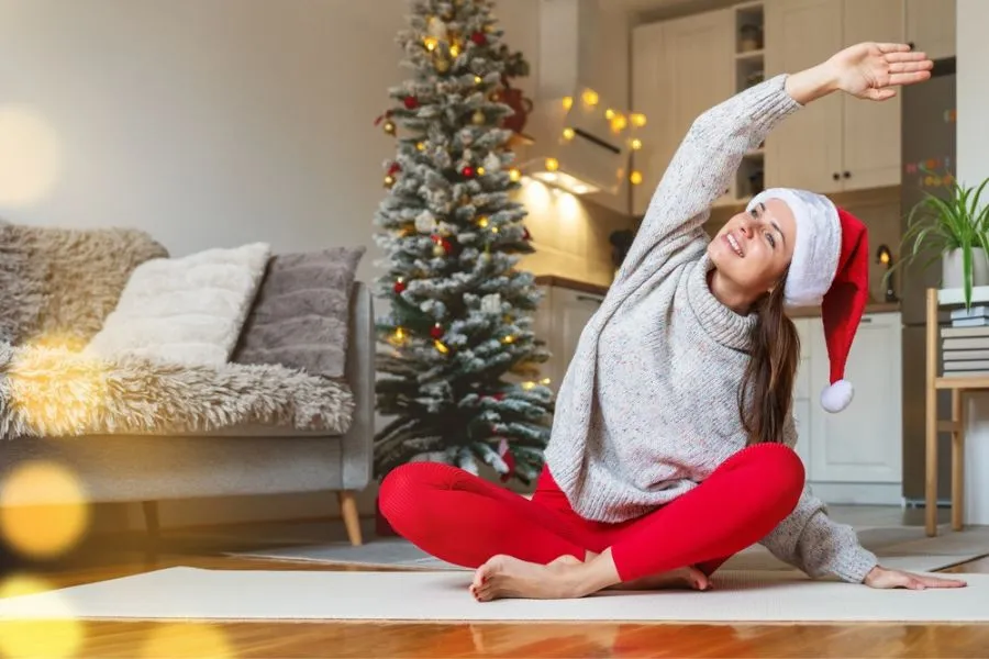 joven haciendo yoga frente a pino navideño