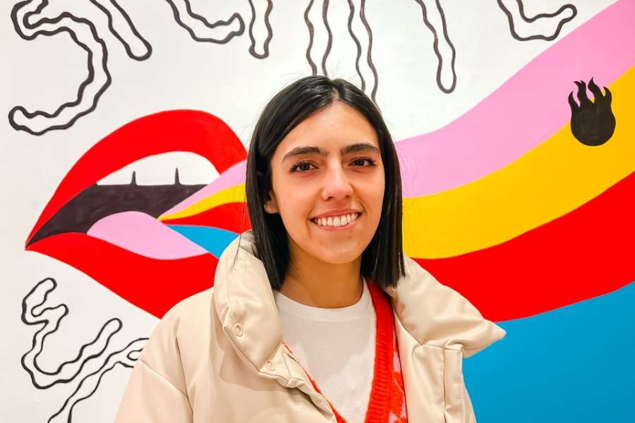 Sara Cansino posando y sonriendo frente al mural de su expo
