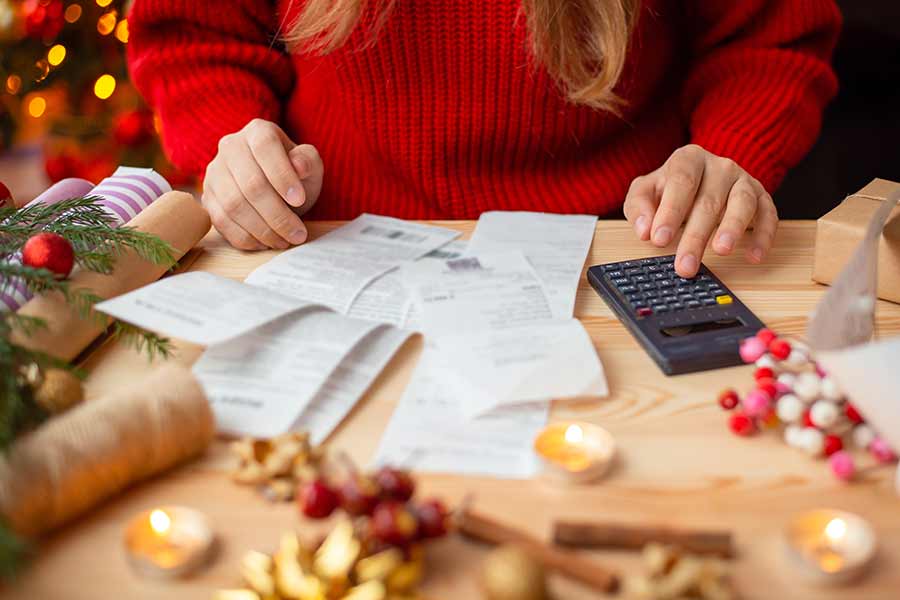 Chica haciendo cuentas en una calculadora, ilustración de cómo hacer rendir el dinero en las compras navideñas y de fin de año