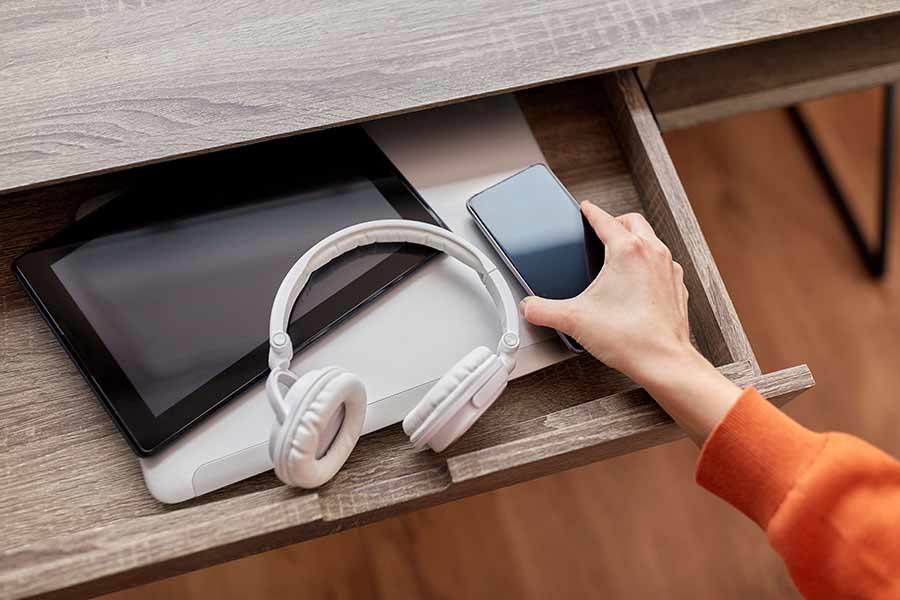 Celular, audífonos y tablet siendo guardados en un cajón, para simbolizar una desintoxicación digital