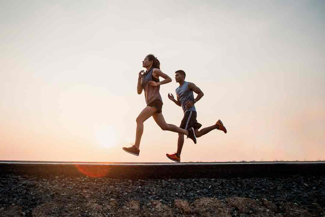 Pareja corriendo para entrenar maraton en atardecer