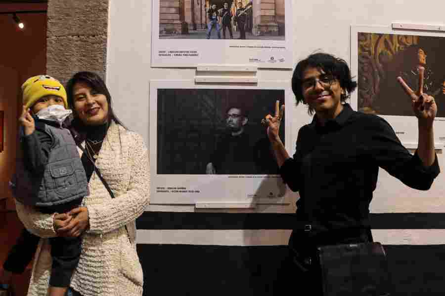 Estudiante de Estudios Creativos junto a sus invitados posando junto su fotografía en el Palacio Municipal.