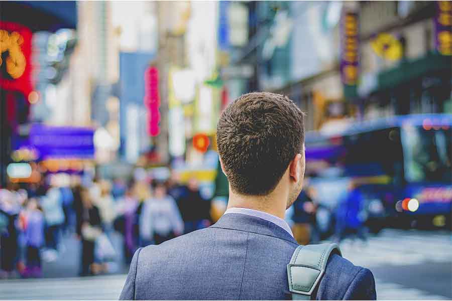 hombre dando la espalda, está vestido con un traje y mirando hacia la calle