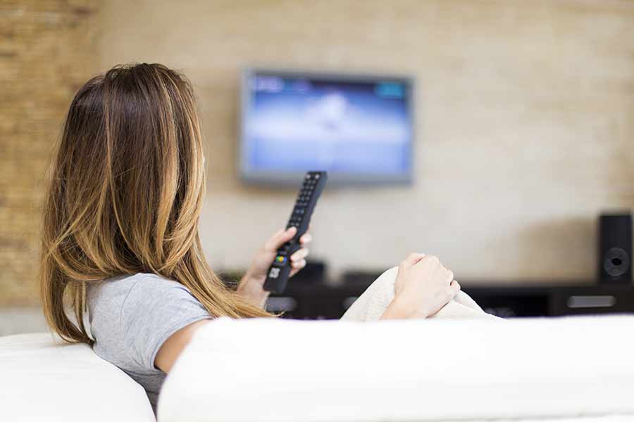 Mujer viendo la televisión en su casa. Evitar este tipo de situaciones al momento de hacer home office
