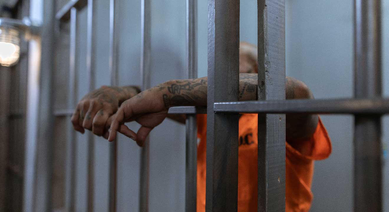 Hombre encarcelado con los brazos fuera de la celda