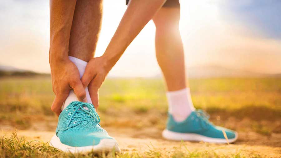 Manos de hombre deportista sosteniendo su tobillo