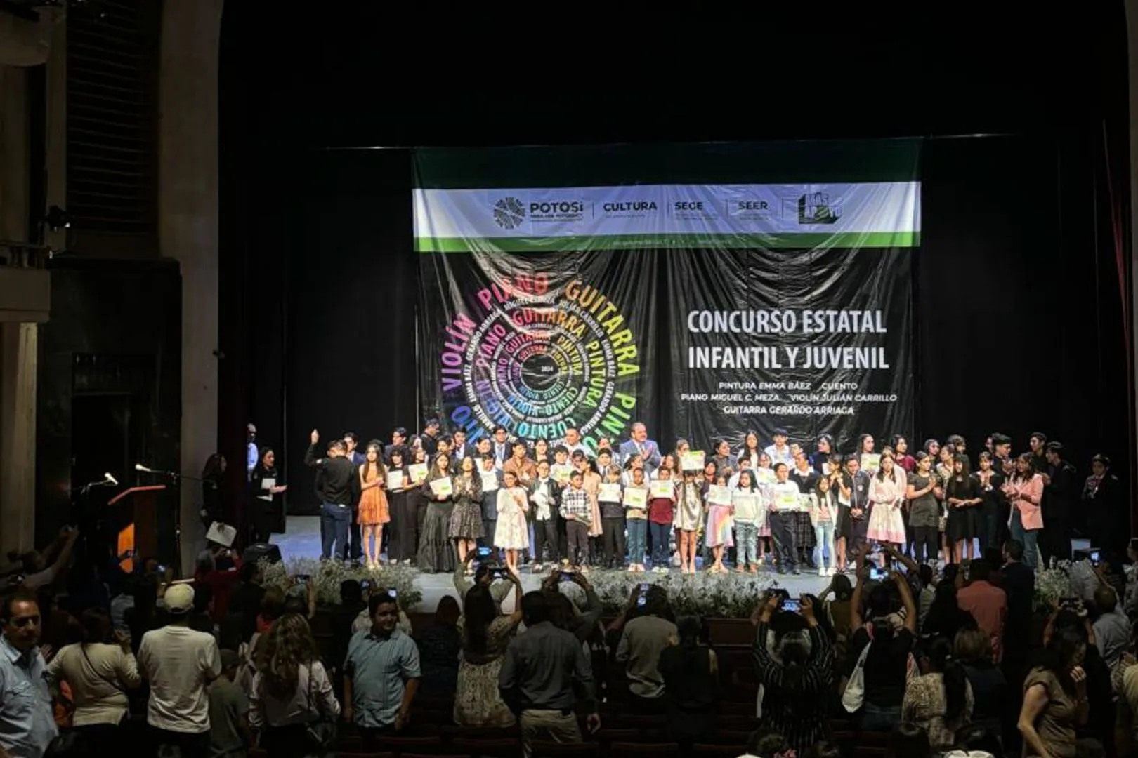 Jóvenes reconocidos en la competencia, están parados sobre un escenario