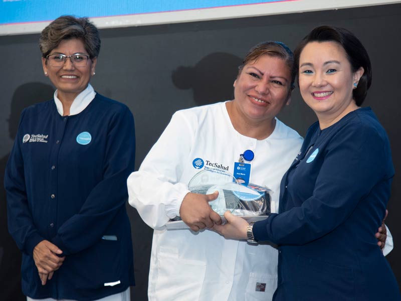Sayuri Komera, directora de Enfermería de TecSalud, entregando un reconocimiento durante el simposio.