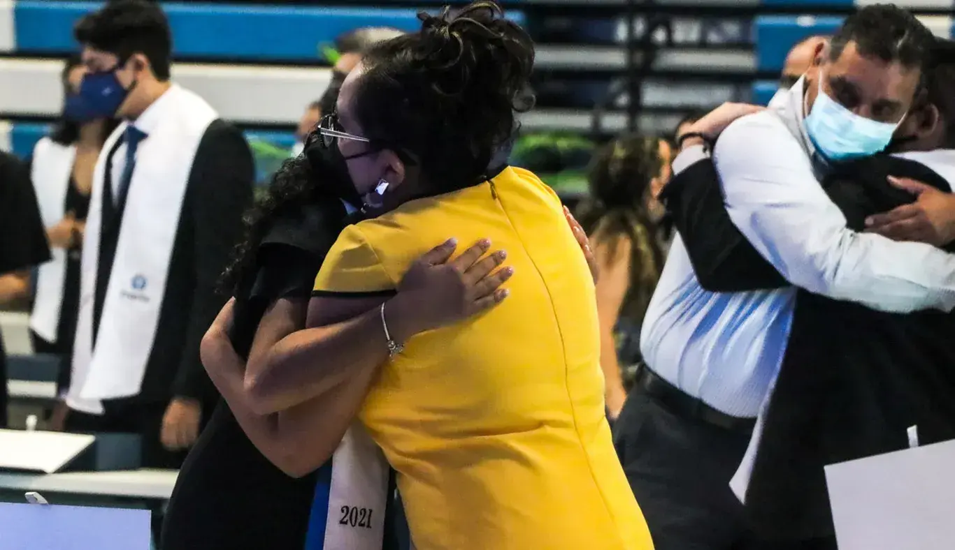 Papás abrazando a sus hijos graduados