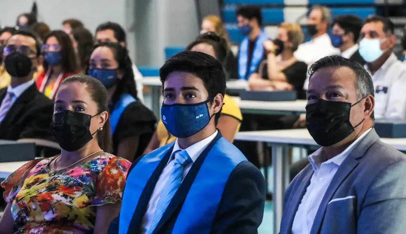 Alumno y papás en ceremonia de graduación
