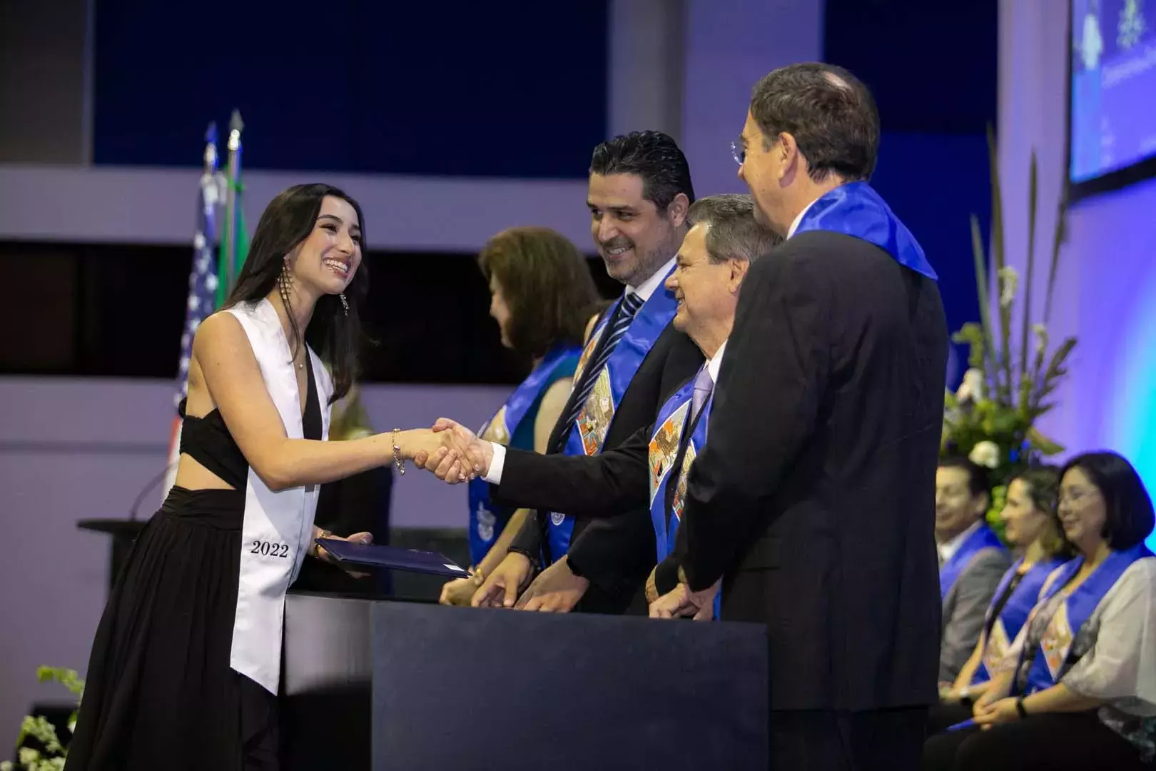 La alumna Andrea Guzmán saludando a miembros del presidium