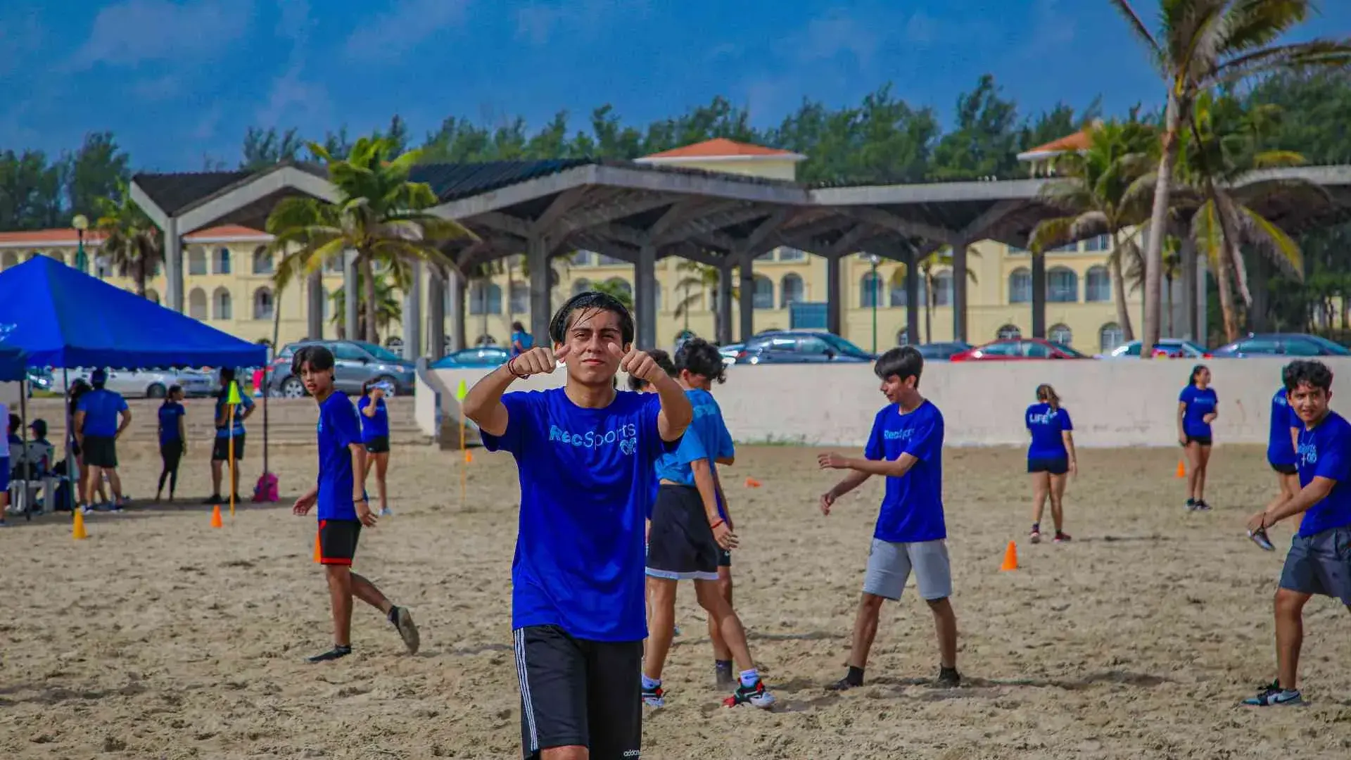Alumno saludando a la cámara en la playa miramar