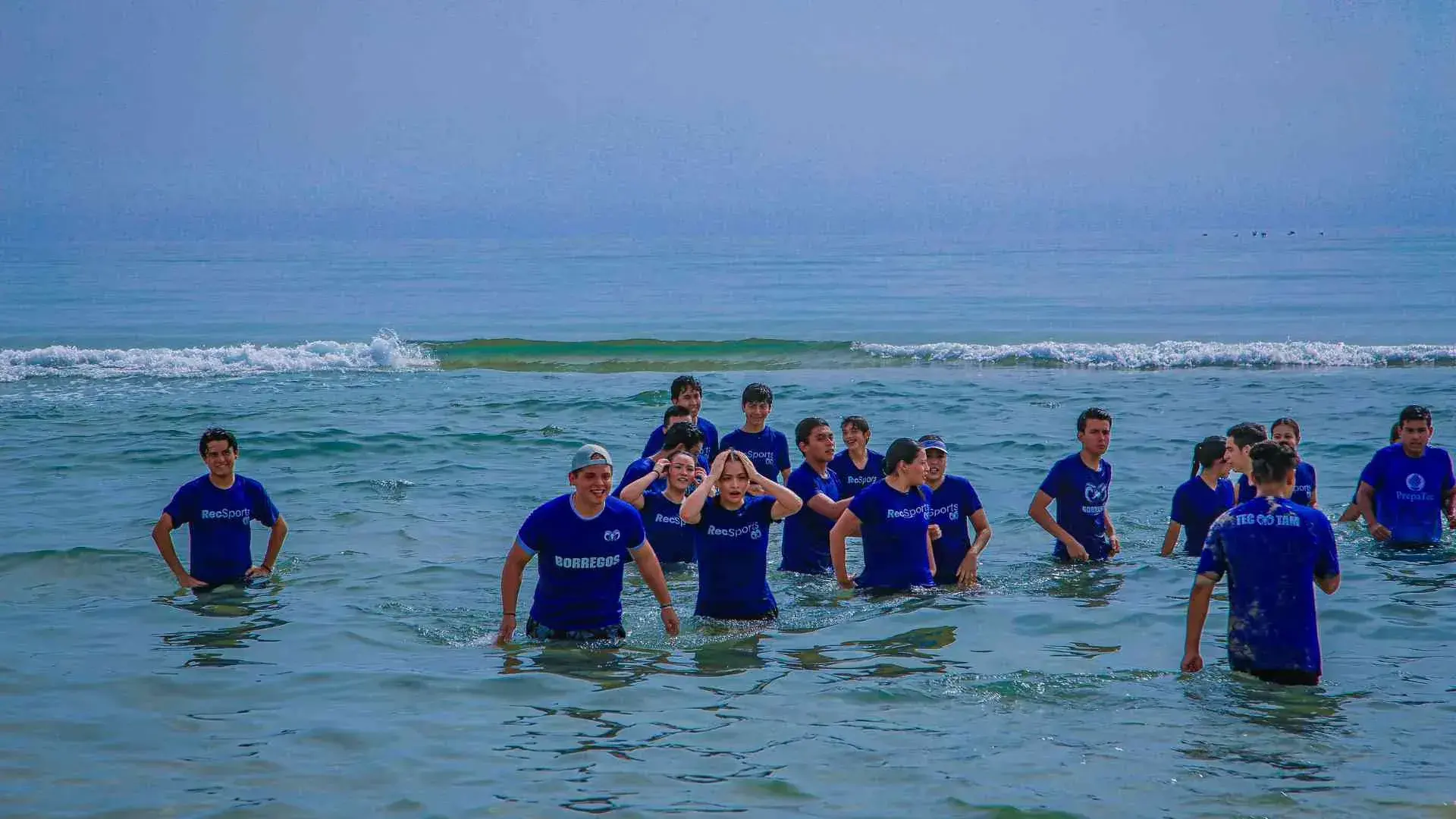 alumnos refrescándose en la orilla de la playa