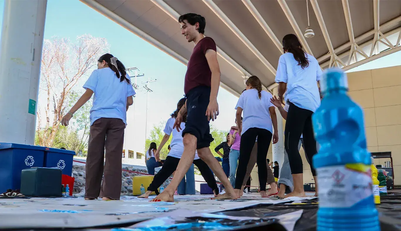 Grupo de alumnos caminando sobre una lona descalzos con los pies cubiertos de pintura.