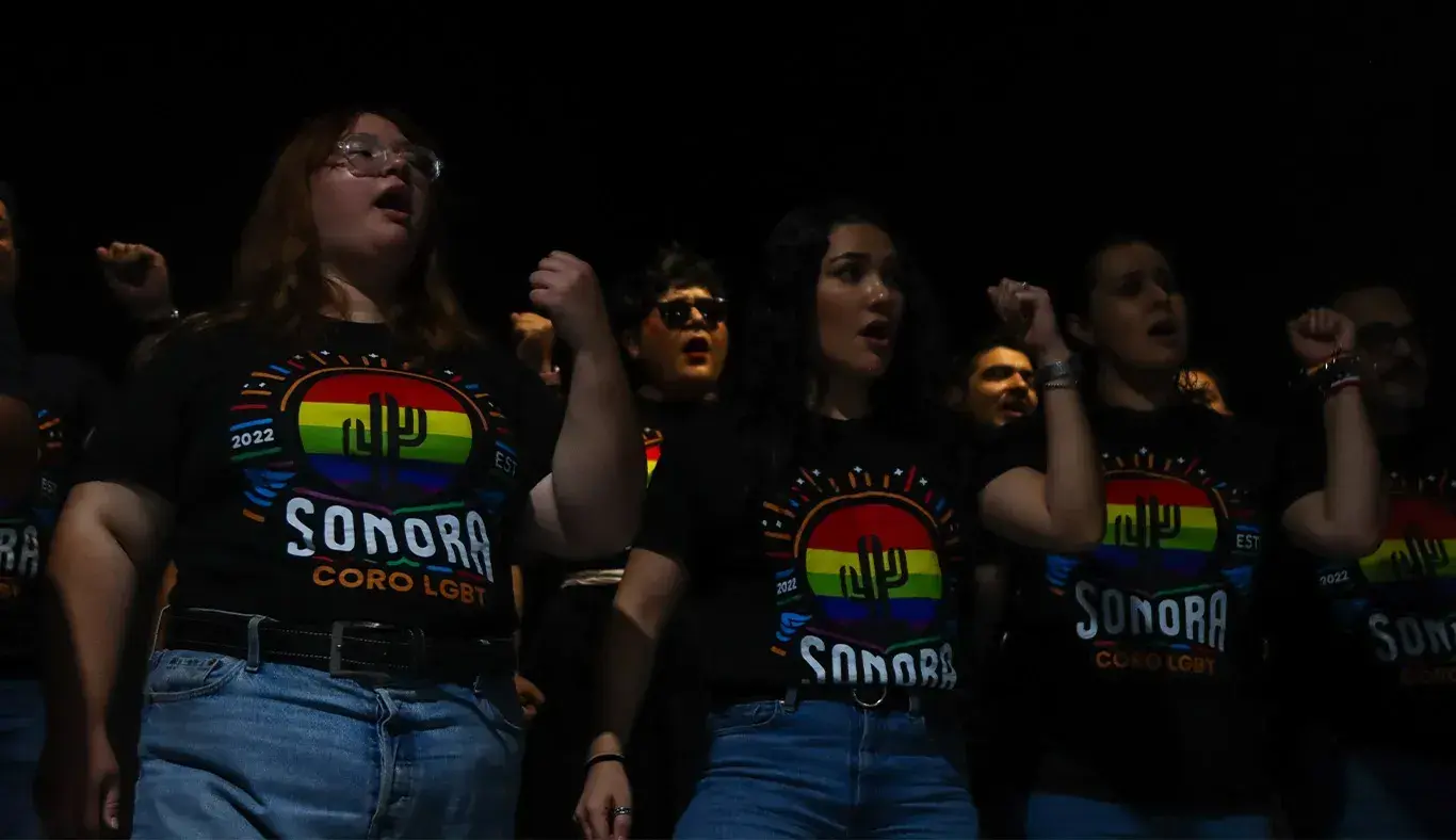 Tres personas cantadno como parte de un coro. 