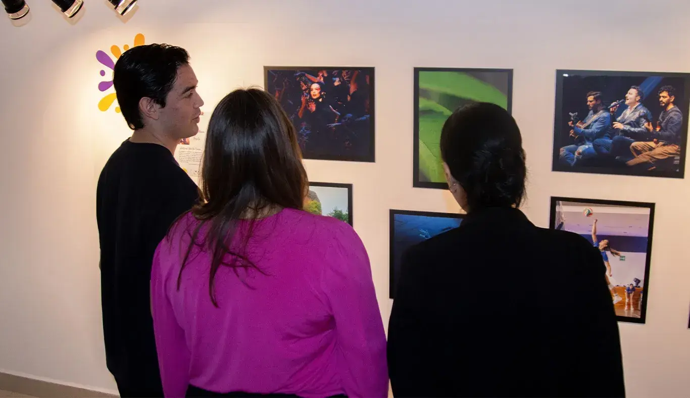 Tres personas de espaldas contemplando una exposición de fotos.