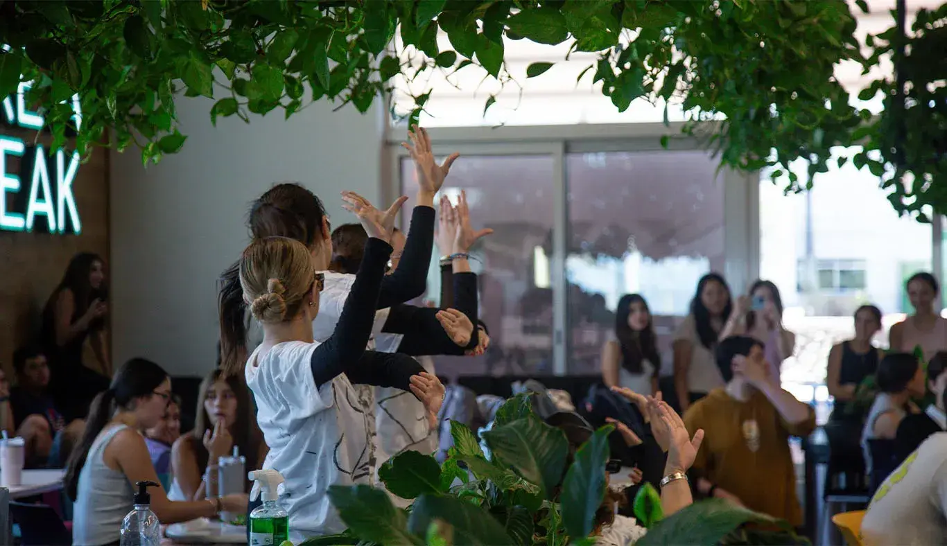 Alumnas bailando entre mesas de una cafetería. 