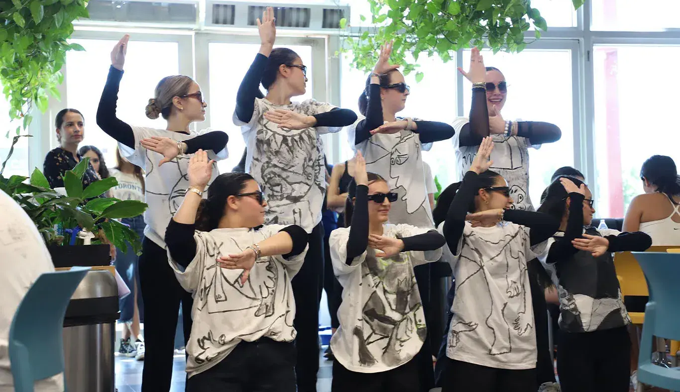 7 chicas acomodadas de forma que los dibujos en sus camisetas forman un dibujo de Picaso. 