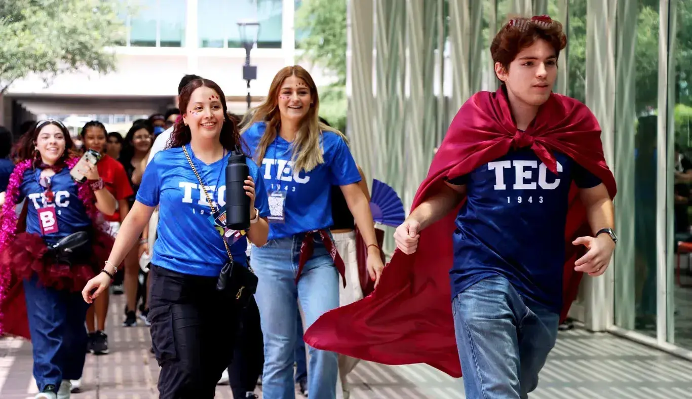 Alumnos corriendo por el campus con capas de color guindo.