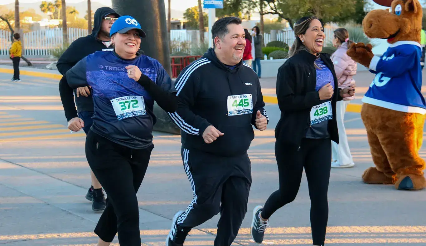 Tres personas corriendo y cruzando la meta