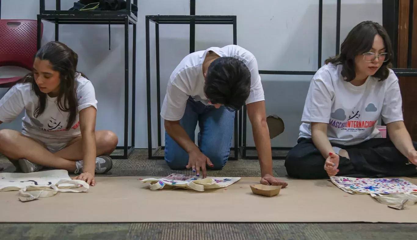 Tres jóvenes dibujando sobre papel kraft.