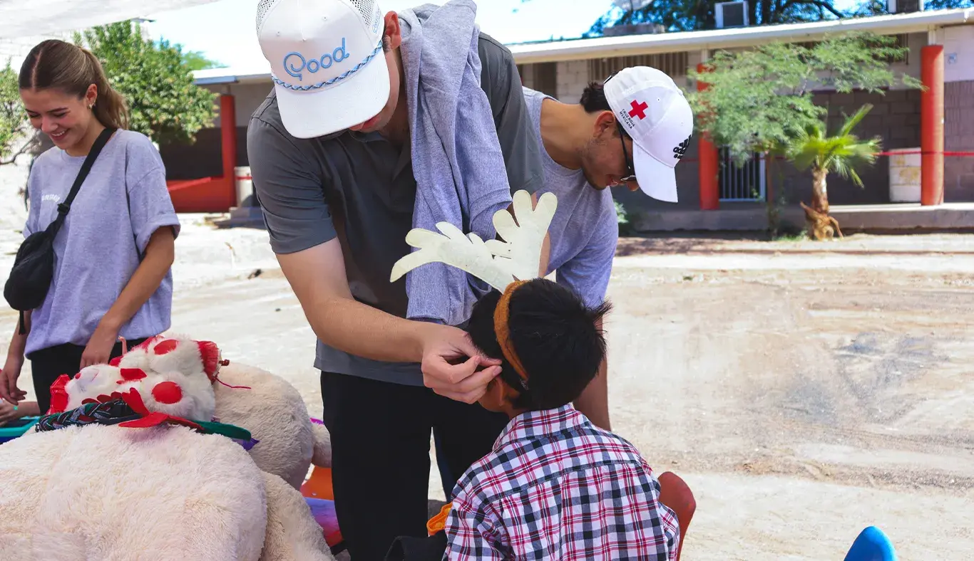 Joven voluntario acomodando diadema con decoración en cabeza de niño.