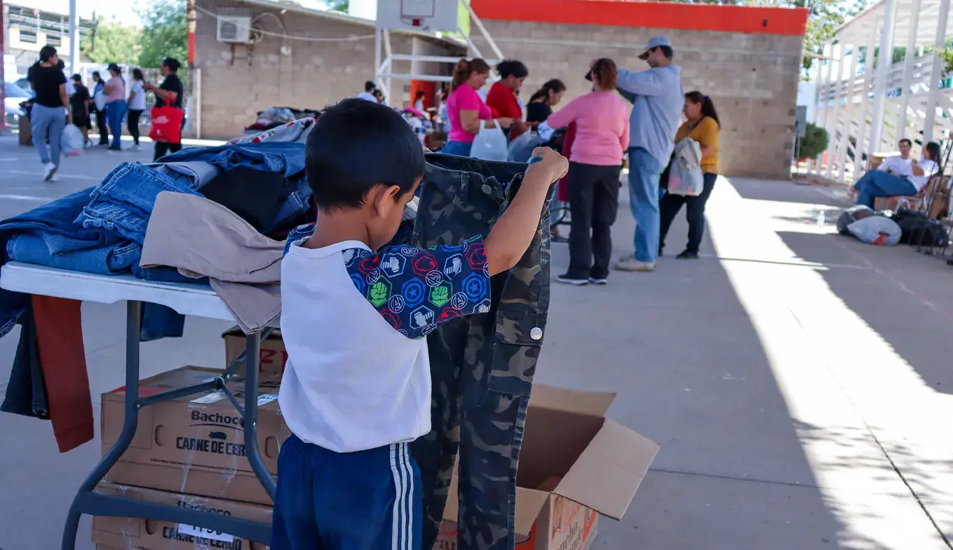 Niño sosteniendo par de pantalones. 