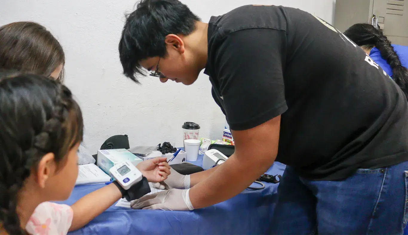 Joven voluntario tomando la presión arterial de una niña. 
