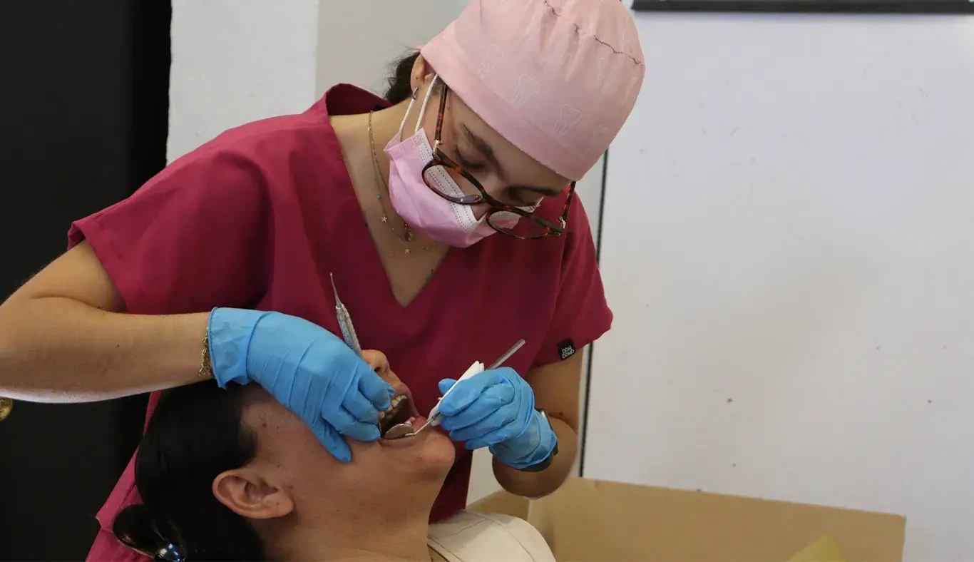 Dentista revisando boca de paciente. 