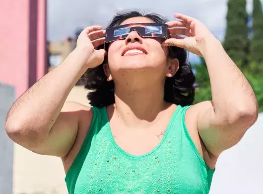 Mujer observa eclipse solar con lentes especiales.