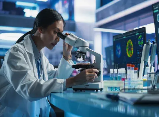 mujer en laboratorio viendo por microscopio