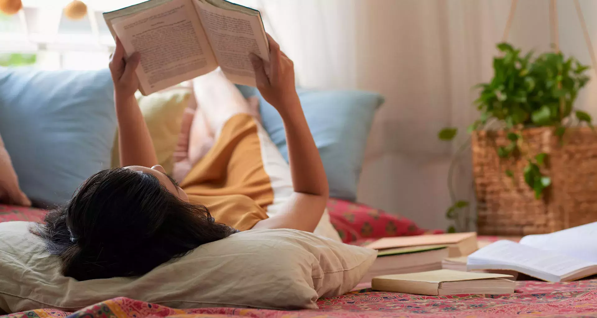 Mujer acostada en el piso de su casa leyendo un libro