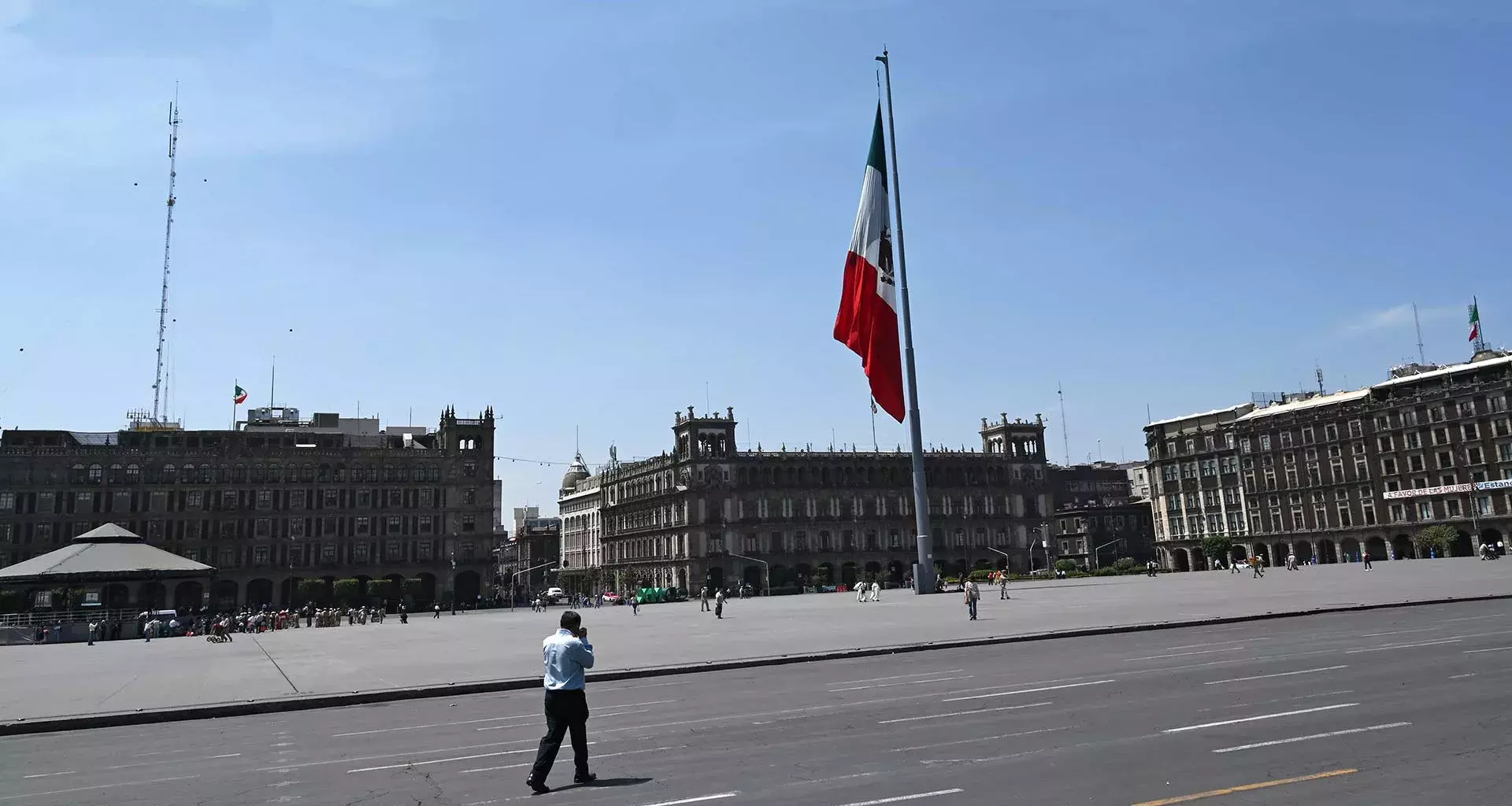 Vista del Zócalo de la Ciudad de México, con una persona caminando por su calle ante el vacío de vehículos