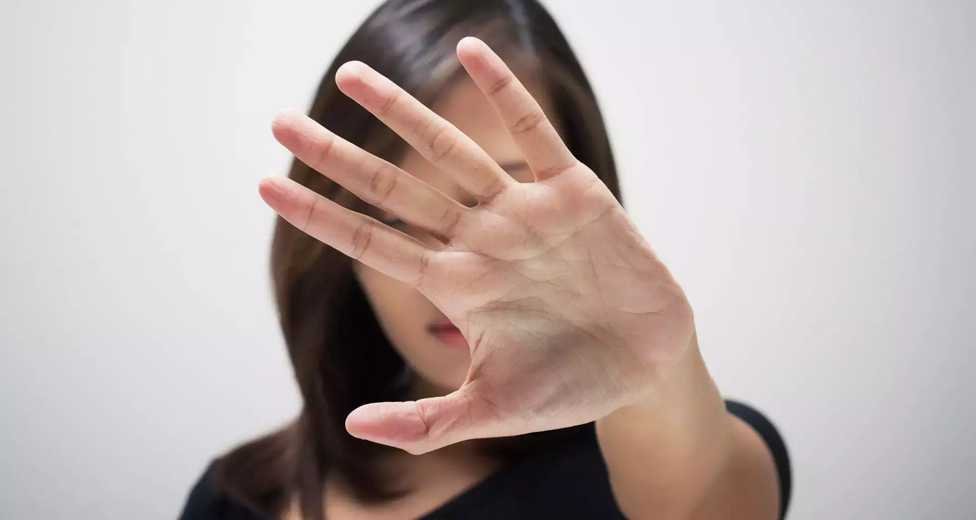 Mujer con palma de la mano abierta, en señal de poner un alto a la violencia de género