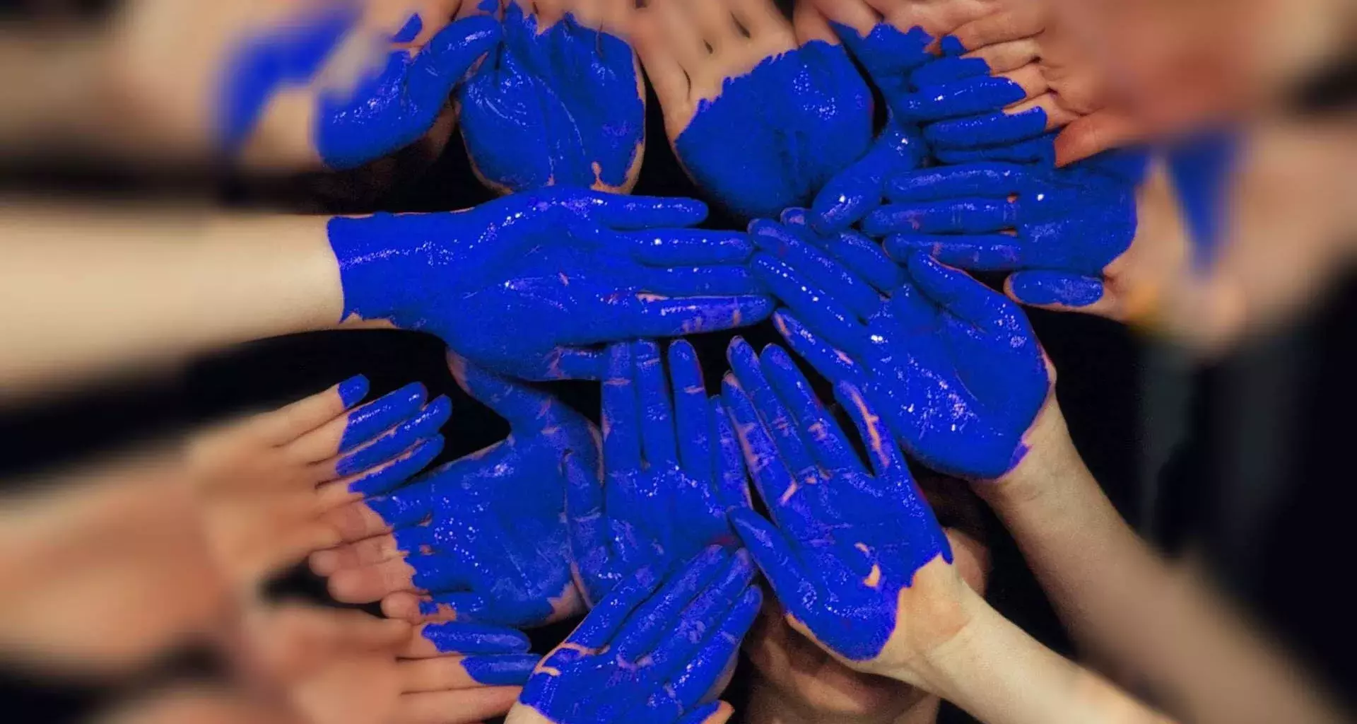 Alumnos de PrepaTec formando un corazón con sus manos pintadas de azul.