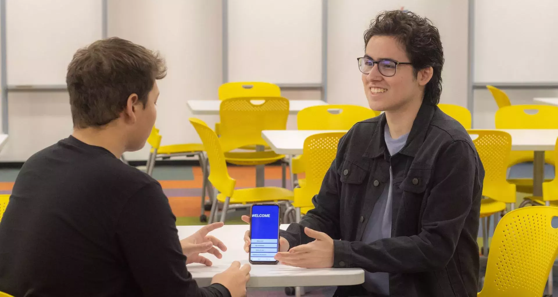 alumno muestra su app de lenguaje de señas en su teléfono
