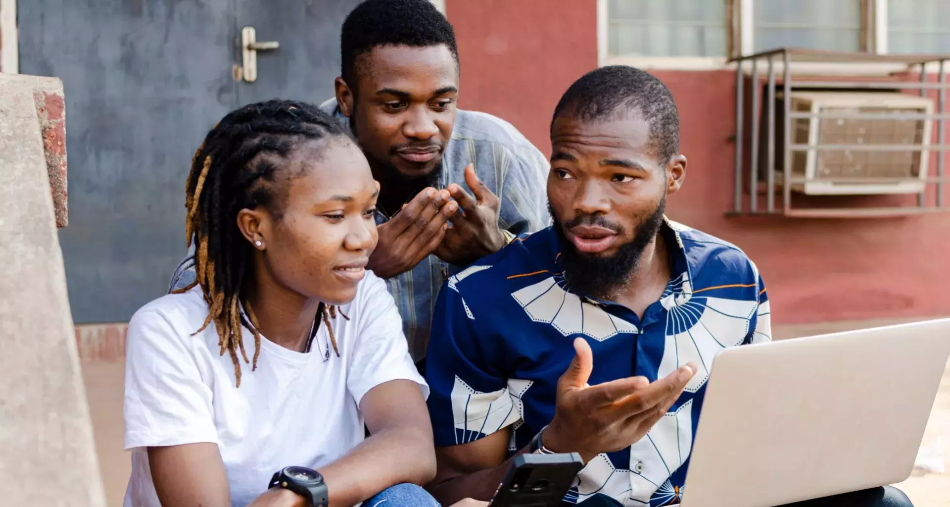 2 jóvenes y 1 chica africana, observando una laptop.