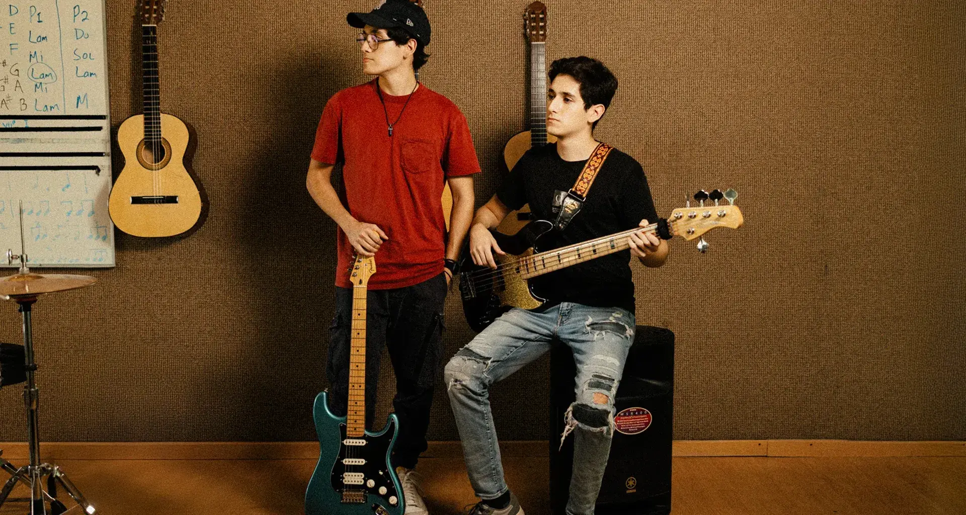 Hermanos posan con guitarra y bajo en espacio musical del Tec de Monterrey
