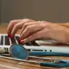 Una mujer escribiendo sobre el teclado de una computadora, a su lado tiene un estetoscopio