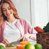 Mujer joven en una cocina cortado un limón con frutas y verduras