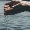 Manos agarrando agua y dejándola caer. 