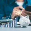 Foto conceptual de una persona calculando sus finanzas, y al frente una alcancía con monedas a lado