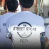 Vista de espaldas de tres voluntarios portando camisetas blancas con un logo que dice Street Store 2025