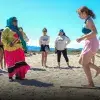 Adolescente hace baile tradicional guiada por un miembro de la comunidad Comca'ac en la playa.