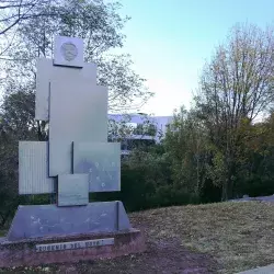 Imagen del monumento en Memoria a Don Eugenio del Hoyo, a un costado de cafeteria, se muestran varias figuras rectangulares, acomodadas una sobre la otra y articuladas verticalmente.