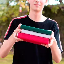 Joven sosteniendo libros verde, blanco y rojo
