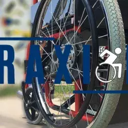 Logo de "Traxión" con el fondo de fotografía de la rueda del silla de ruedas eléctrica