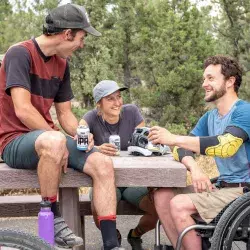 Hombre en silla de ruedas platicando con sus amigos en el bosque