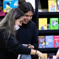 Dos mujeres jóvenes buscan libros en la FIL Monterrey 2022