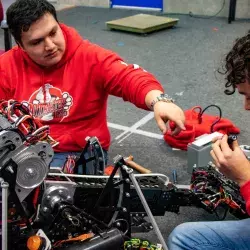 El coach Francisco Rosas ayudando a un estudiante con el robot.